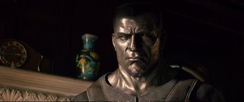 Movie still from “Deadpool 2” (2018), directed by David Leitch – A silver statue of a man with a serious look on his face; Close Up shot, Low angle