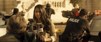 Movie still from “Deadpool 2” (2018), directed by David Leitch – A woman is holding a microphone while standing in front of a camera; Medium shot, Over the shoulder angle