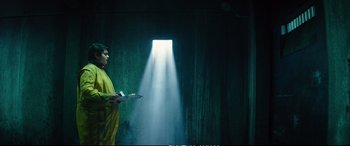 Movie still from “Deadpool 2” (2018), directed by David Leitch – A man in a yellow raincoat standing in front of an open window; Medium shot, Low angle