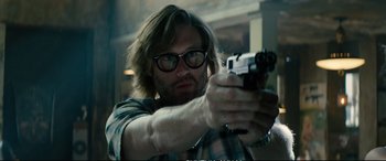 Movie still from “Deadpool 2” (2018), directed by David Leitch – A man with glasses is holding a gun; Close Up shot, Over the shoulder angle