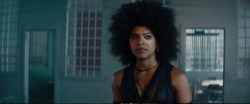 Movie still from “Deadpool 2” (2018), directed by David Leitch – A woman with a large afro is standing in a dark room; Close Up shot, Over the shoulder angle