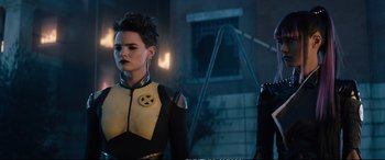 Movie still from “Deadpool 2” (2018), directed by David Leitch – A woman in a yellow and black outfit standing next to a man; Medium shot, Over the shoulder angle