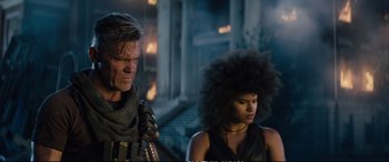 Movie still from “Deadpool 2” (2018), directed by David Leitch – A man standing next to a woman in a black dress; Medium shot, Low angle