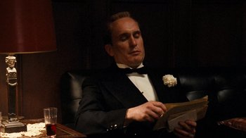 Movie still from “The Godfather” (1972), directed by Francis Ford Coppola – A man in a tuxedo sitting at a table with a book; Medium shot, Low angle