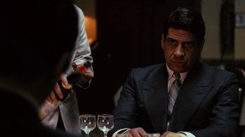 Movie still from “The Godfather” (1972), directed by Francis Ford Coppola – A man sitting at a dinner table with two other men; Close Up shot, Over the shoulder angle
