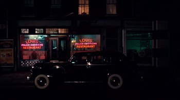 Movie still from “The Godfather” (1972), directed by Francis Ford Coppola – An old car parked on the side of the street; Extreme Wide shot, High angle
