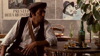 Movie still from “The Godfather” (1972), directed by Francis Ford Coppola – A man sitting at a table with a glass of whiskey; Medium shot, Over the shoulder angle