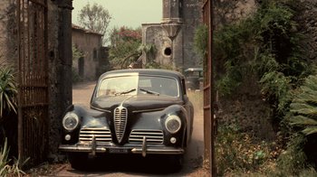 Movie still from “The Godfather” (1972), directed by Francis Ford Coppola – An old car parked on the side of the road; Wide shot, Low angle