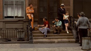 Movie still from “The Godfather” (1972), directed by Francis Ford Coppola – A group of people sitting on the steps of a building; Wide shot, High angle