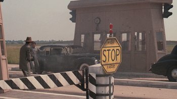Movie still from “The Godfather” (1972), directed by Francis Ford Coppola – A stop sign is shown with an old car in the background; Wide shot, Over the shoulder angle