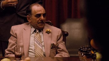 Movie still from “The Godfather” (1972), directed by Francis Ford Coppola – An older man sitting in a chair wearing a suit and tie; Medium shot, Low angle