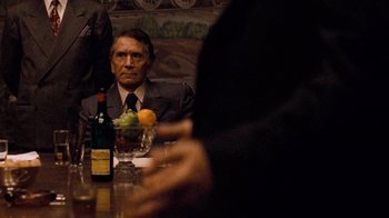 Movie still from “The Godfather” (1972), directed by Francis Ford Coppola – An older man sitting at a table with a glass of wine; Medium shot, Over the shoulder angle
