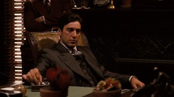 Movie still from “The Godfather” (1972), directed by Francis Ford Coppola – A man sitting at a table in a suit and tie; Medium shot, Low angle