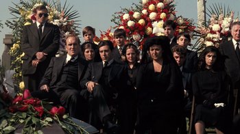 Movie still from “The Godfather” (1972), directed by Francis Ford Coppola – A group of people in black suits and flowers; Wide shot, Low angle