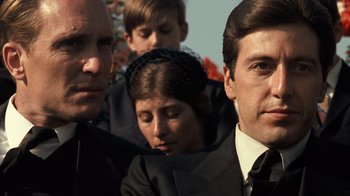Movie still from “The Godfather” (1972), directed by Francis Ford Coppola – A group of men and women in suits and ties; Close Up shot, Over the shoulder angle