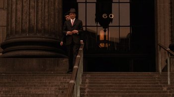 Movie still from “The Godfather” (1972), directed by Francis Ford Coppola – A man in a suit and hat standing at the top of a set of stairs; Wide shot, Low angle