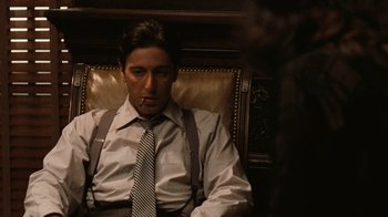 Movie still from “The Godfather” (1972), directed by Francis Ford Coppola – A man sitting in a chair smoking a cigarette; Medium shot, Low angle