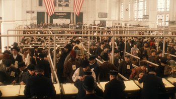 Movie still from “The Godfather Part II” (1974), directed by Francis Ford Coppola – A group of people sitting in a room with american flags in the background; Wide shot, High angle