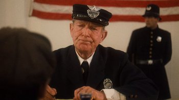 Movie still from “The Godfather Part II” (1974), directed by Francis Ford Coppola – An older man in a uniform sitting in front of an american flag; Close Up shot, Over the shoulder angle