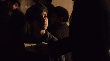 Movie still from “The Godfather Part II” (1974), directed by Francis Ford Coppola – A young boy in a hat looking at something; Close Up shot, Over the shoulder angle