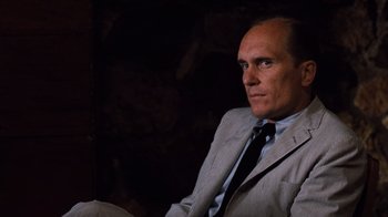 Movie still from “The Godfather Part II” (1974), directed by Francis Ford Coppola – A man wearing a suit and tie sitting in a chair; Close Up shot, Over the shoulder angle