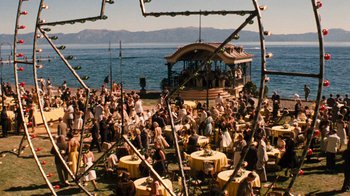 Movie still from “The Godfather Part II” (1974), directed by Francis Ford Coppola – A crowd of people sitting around tables near the water; Extreme Wide shot, High angle