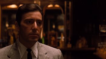 Movie still from “The Godfather Part II” (1974), directed by Francis Ford Coppola – A person wearing a suit and tie; Close Up shot, Over the shoulder angle