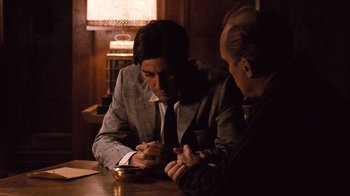 Movie still from “The Godfather Part II” (1974), directed by Francis Ford Coppola – Two men sitting at a wooden table in a room; Medium shot, Over the shoulder angle