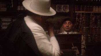 Movie still from “The Godfather Part II” (1974), directed by Francis Ford Coppola – A man wearing a white hat and a white suit; Close Up shot, Over the shoulder angle