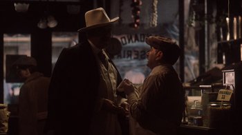Movie still from “The Godfather Part II” (1974), directed by Francis Ford Coppola – Two men are talking in a bar at night; Medium shot, Over the shoulder angle