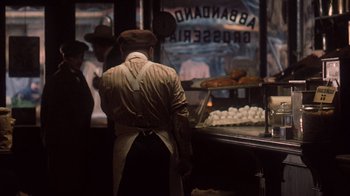 Movie still from “The Godfather Part II” (1974), directed by Francis Ford Coppola – A man standing in front of an oven with food; Medium shot, High angle