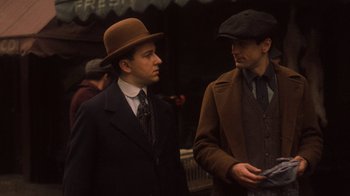 Movie still from “The Godfather Part II” (1974), directed by Francis Ford Coppola – Two men in hats and suits stand next to each other; Medium shot, Over the shoulder angle