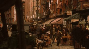 Movie still from “The Godfather Part II” (1974), directed by Francis Ford Coppola – A group of people standing on a city street near buildings; Wide shot, High angle