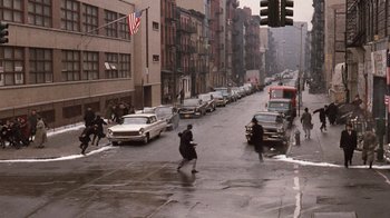 Movie still from “The Godfather Part II” (1974), directed by Francis Ford Coppola – A man riding a bike down the middle of a street; Extreme Wide shot, High angle