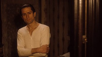 Movie still from “The Godfather Part II” (1974), directed by Francis Ford Coppola – A man standing with his arms crossed in front of a wall; Close Up shot, Over the shoulder angle