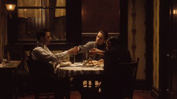 Movie still from “The Godfather Part II” (1974), directed by Francis Ford Coppola – A group of people sitting at a table eating food; Medium shot, High angle