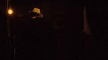 Movie still from “The Godfather Part II” (1974), directed by Francis Ford Coppola – A man wearing a hat in a dark room; Medium shot, Over the shoulder angle