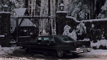 Movie still from “The Godfather Part II” (1974), directed by Francis Ford Coppola – An old car parked in front of a gate in the snow; Wide shot, High angle