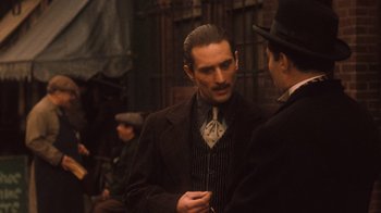 Movie still from “The Godfather Part II” (1974), directed by Francis Ford Coppola – A man in a top hat talking to another man in a suit; Medium shot, Over the shoulder angle