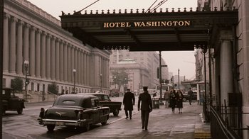 Movie still from “The Godfather Part II” (1974), directed by Francis Ford Coppola – A group of people walking down a street under an overpass; Wide shot, Low angle