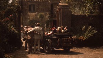 Movie still from “The Godfather Part II” (1974), directed by Francis Ford Coppola – A group of people standing around a car; Wide shot, High angle