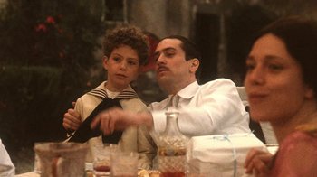 Movie still from “The Godfather Part II” (1974), directed by Francis Ford Coppola – A man and a young boy sitting at a table; Medium shot, Over the shoulder angle