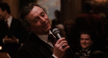 Movie still from “The Godfather Part III” (1990), directed by Francis Ford Coppola – A man holding a microphone in his hand; Close Up shot, Over the shoulder angle