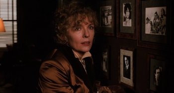 Movie still from “The Godfather Part III” (1990), directed by Francis Ford Coppola – A woman sitting in front of a wall of pictures; Close Up shot, Over the shoulder angle