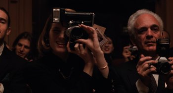 Movie still from “The Godfather Part III” (1990), directed by Francis Ford Coppola – A woman taking a picture with a camera; Close Up shot, Over the shoulder angle