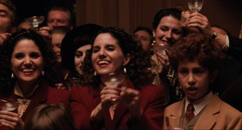 Movie still from “The Godfather Part III” (1990), directed by Francis Ford Coppola – A group of people are gathered around a woman holding a wine glass; Close Up shot, Low angle