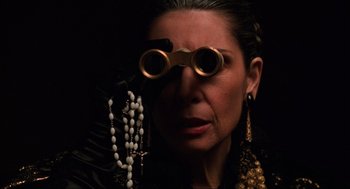 Movie still from “The Godfather Part III” (1990), directed by Francis Ford Coppola – A woman wearing a pair of goggles and a necklace; Close Up shot, Over the shoulder angle