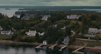 Movie still from “The Good House” (2021), directed by Maya Forbes – An aerial view of houses on the shore of a body of water; Extreme Wide shot, High angle