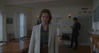 Movie still from “The Good House” (2021), directed by Maya Forbes – A woman standing in a room wearing a white jacket; Medium shot, Over the shoulder angle