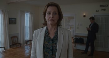 Movie still from “The Good House” (2021), directed by Maya Forbes – A woman wearing a white jacket standing in a living room; Medium shot, Low angle